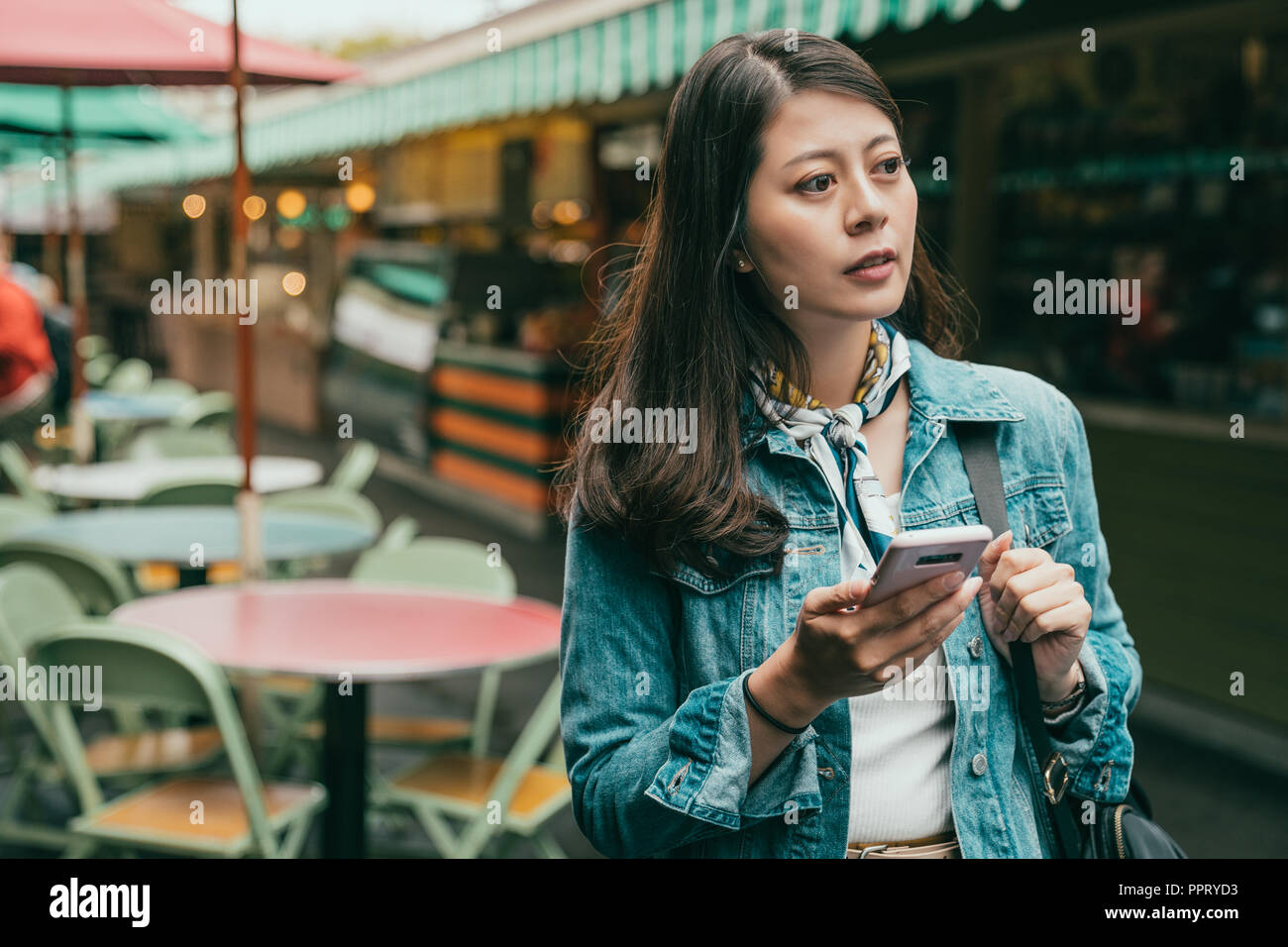 Jeune femme marche et en utilisant son téléphone portable pour trouver la bonne direction Banque D'Images