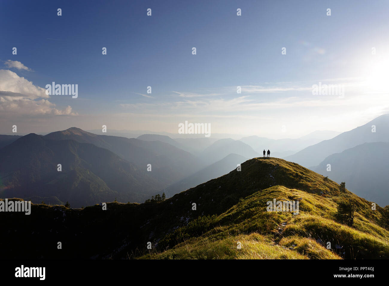 Deux hommes debout sur le dessus de la montagne couverte d'herbe regarder superbe panorama au coucher du soleil Banque D'Images
