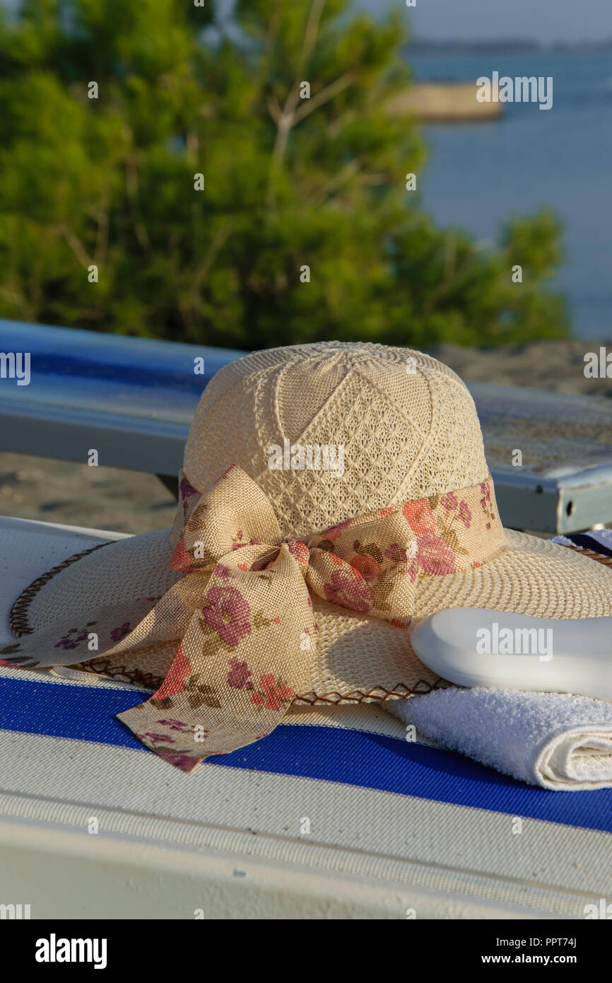 Close up of summer hat, serviette et crème solaire sur un transat Banque D'Images