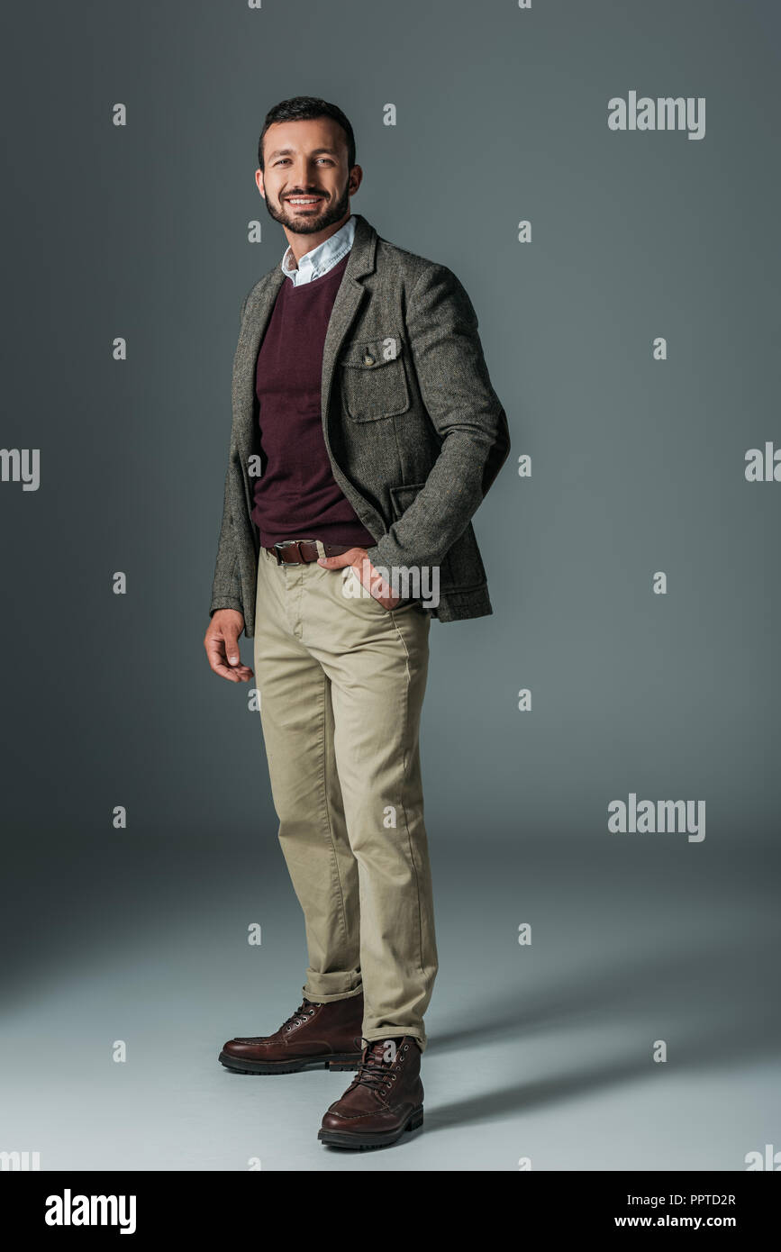 Modèle masculin élégant pantalon beige et posant en tweed veste, sur gris  Photo Stock - Alamy