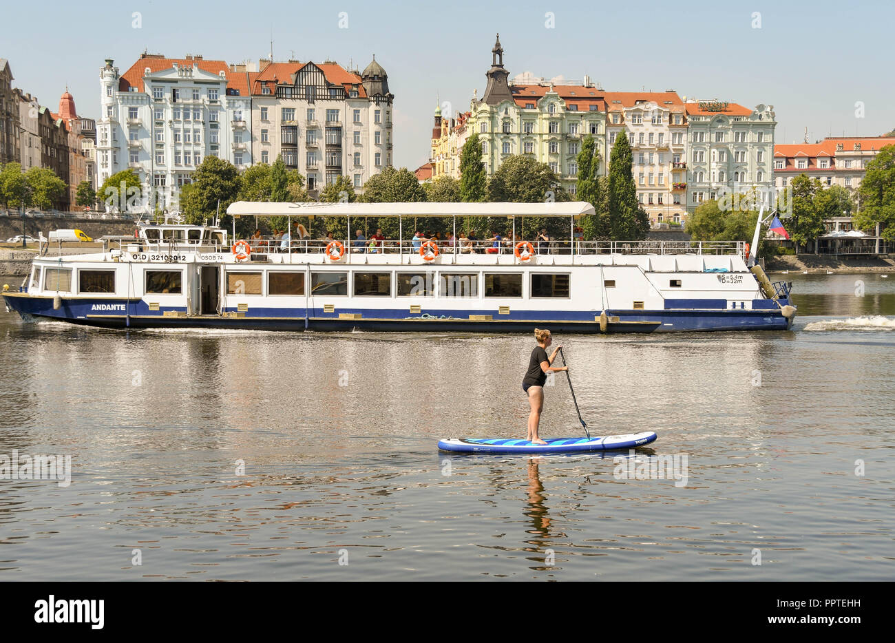 Personne paddle sur le Fleuve Vltava dans le centre de Prague, en République tchèque, en passant d'un bateau de croisière touristique. Banque D'Images