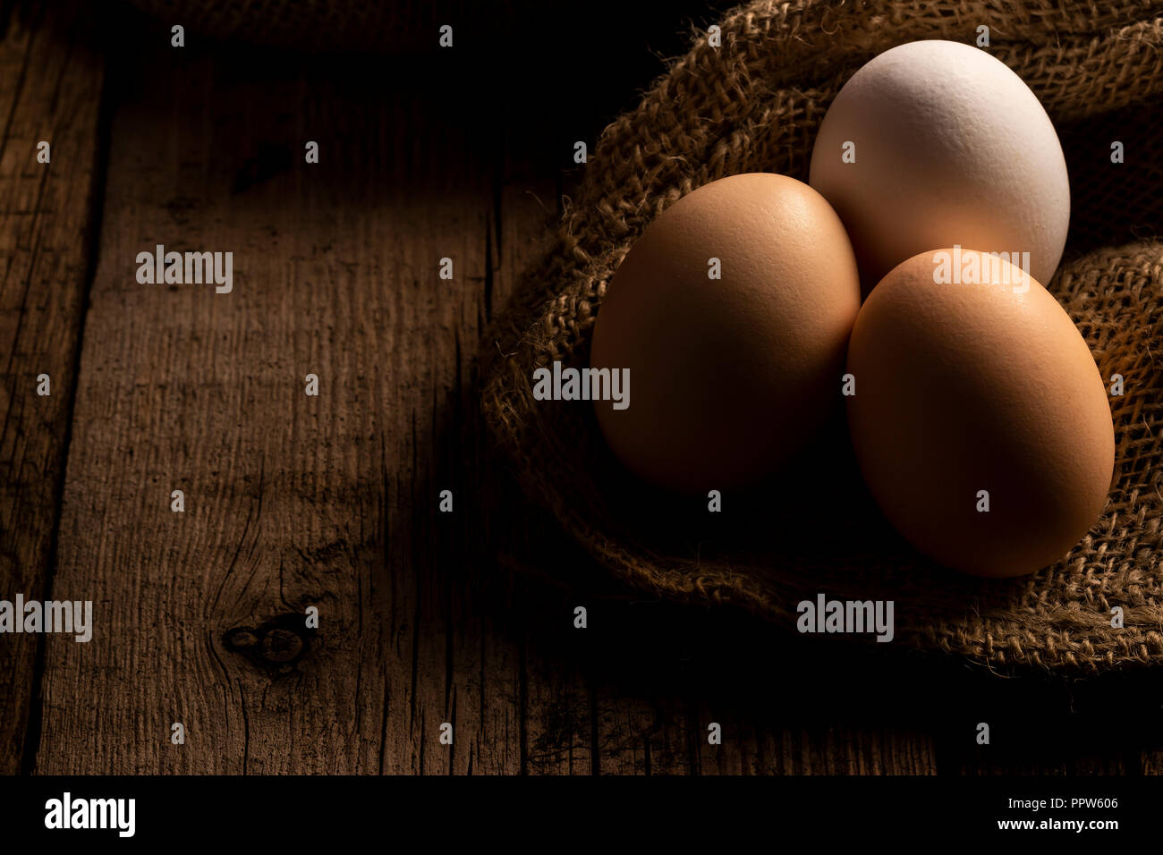 Les oeufs de poulet frais dans farm couché sur toile sur table en bois Banque D'Images