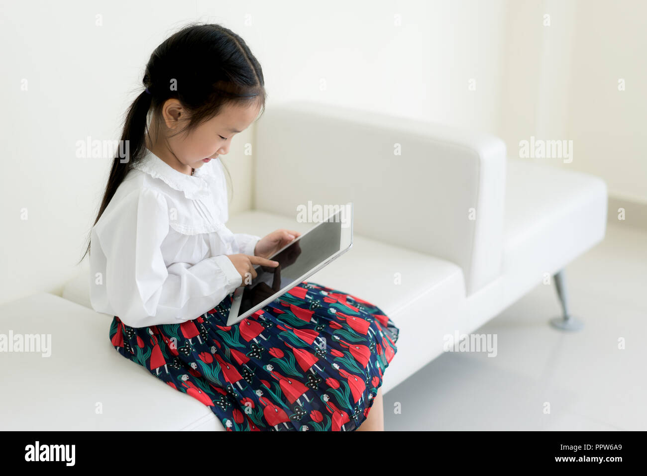 Petite fille asiatique jouant digital tablet. L'éducation, de la science, de la technologie, les enfants et personnes concept. Banque D'Images
