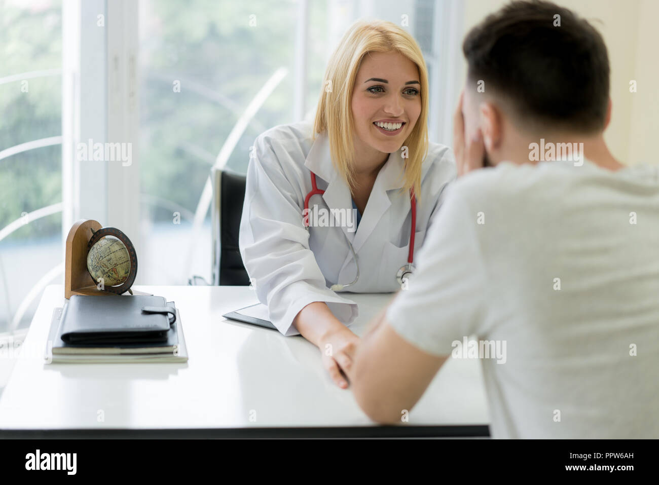 Friendly femme médecin mains tenant la main du patient assis au bureau d'encouragement, de l'empathie, l'acclamer et de soutien alors que l'examen médical. Mauvaise n Banque D'Images