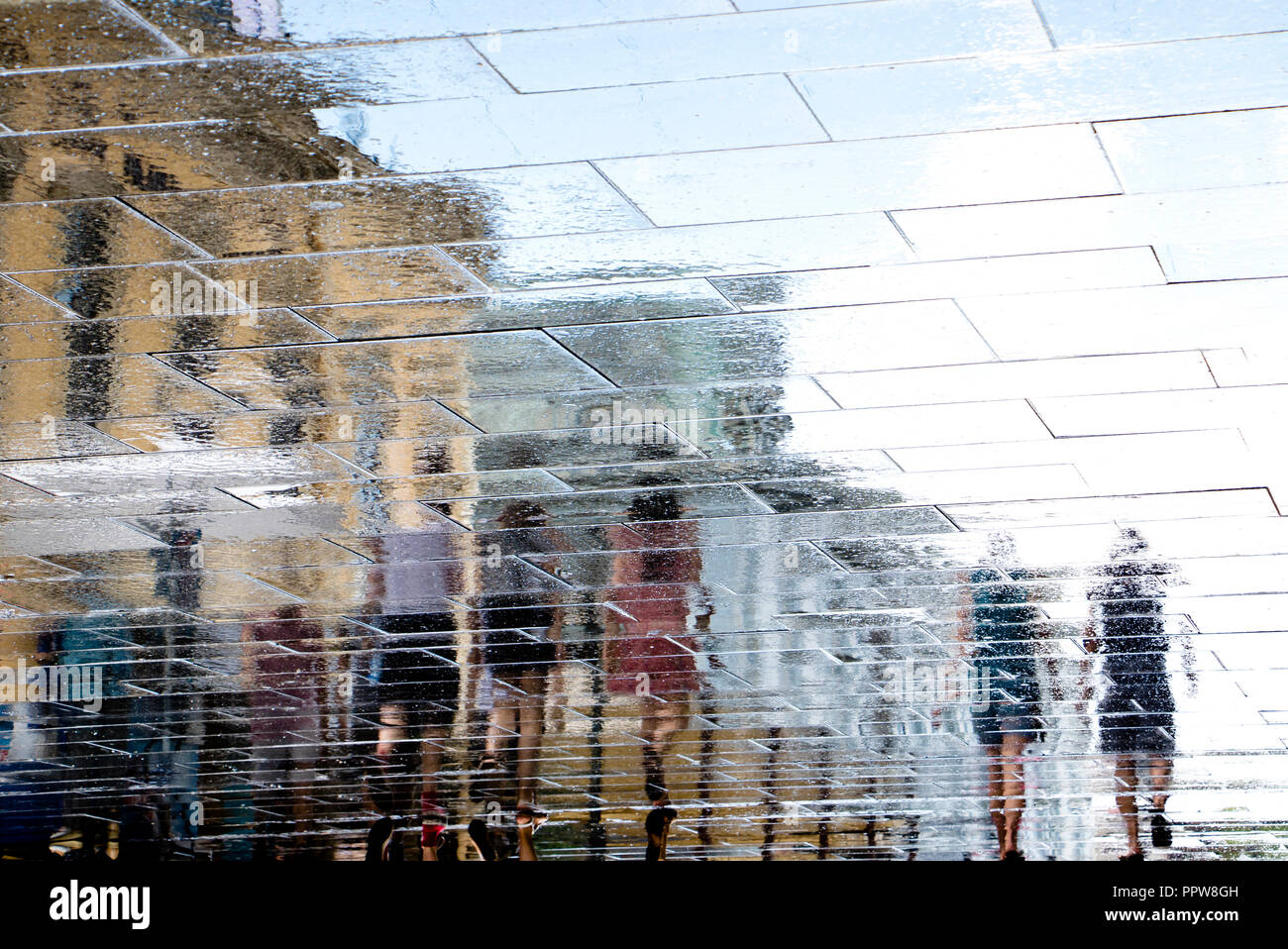 Réflexion floue ombre silhouette dans une flaque de personnes marchant sur la rue ville humide après la pluie Banque D'Images