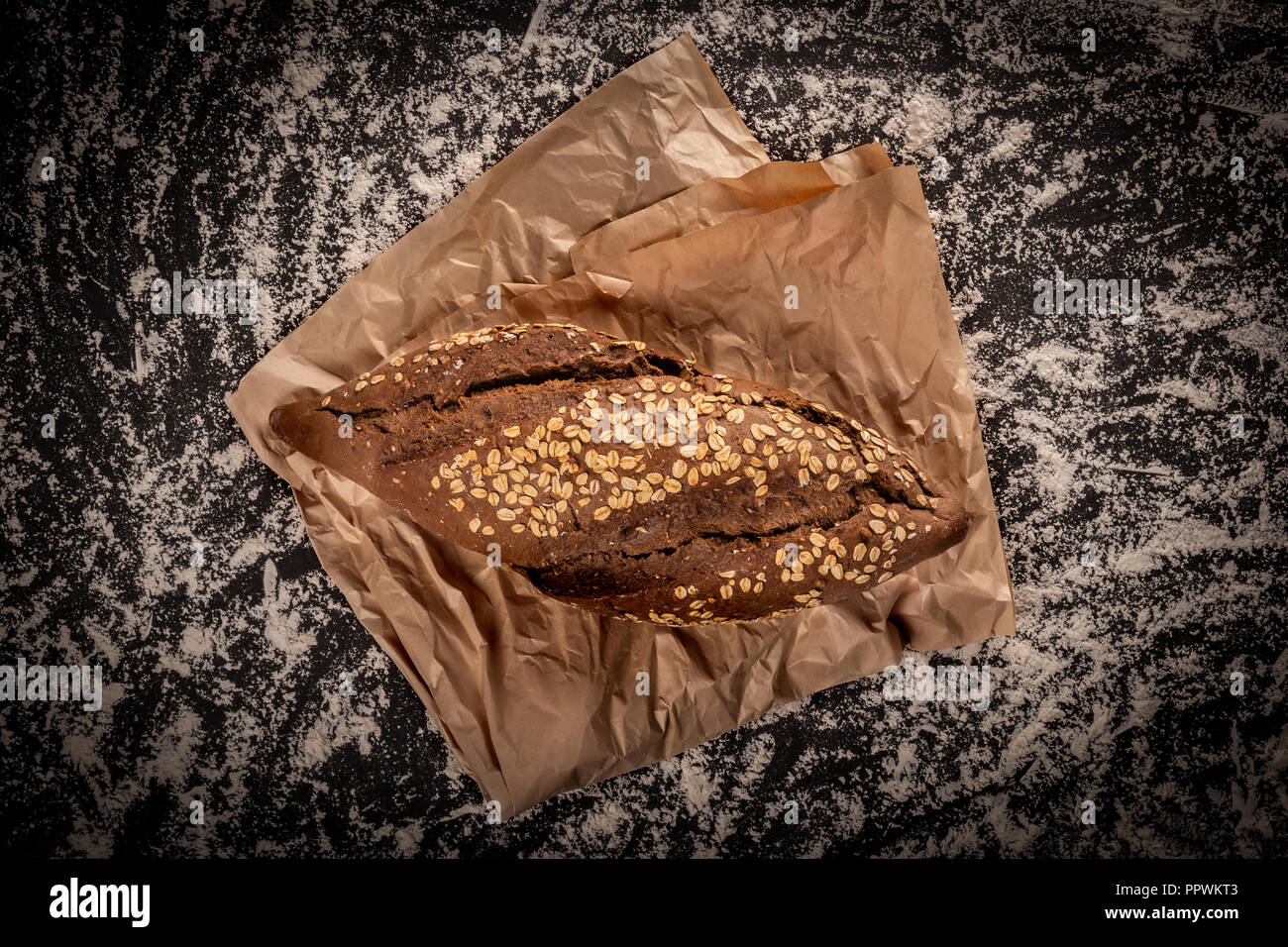 Au-dessus de big shot de pain de seigle avec l'avoine sur morceau de papier sulfurisé sur le dessus de table dans la farine blanche Banque D'Images