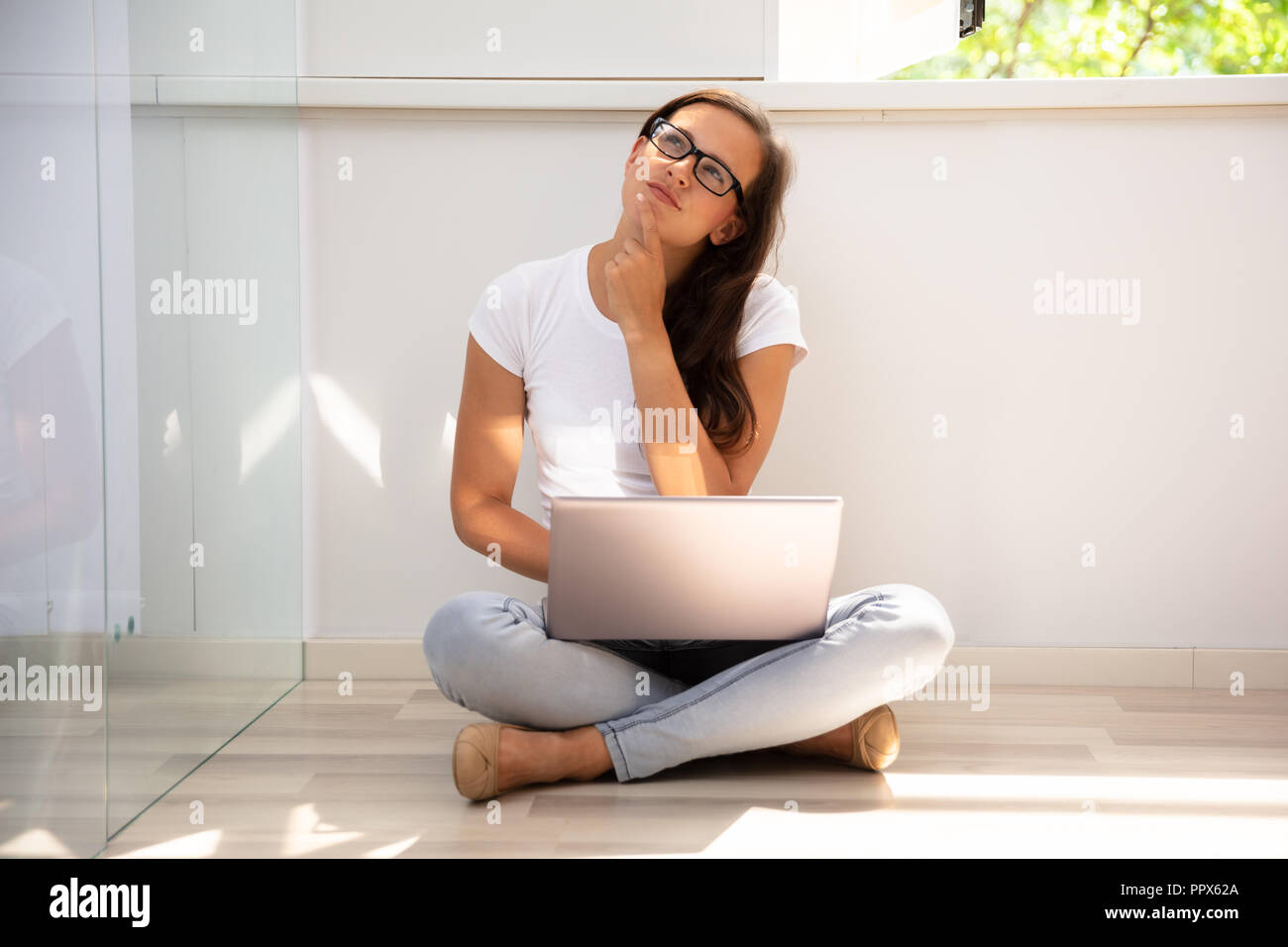 Young Woman Sitting on Floor Using Laptop At Home Banque D'Images