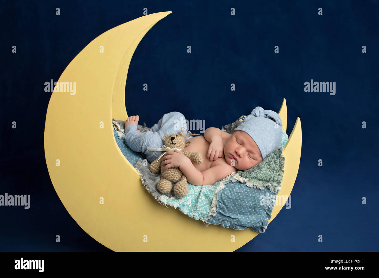 Studio portrait d'un nouveau-né âgé de dix jours en portant des bas de pyjama bébé garçon et un coin couchage. Il est en train de dormir sur une lune posing and holding a prop Banque D'Images