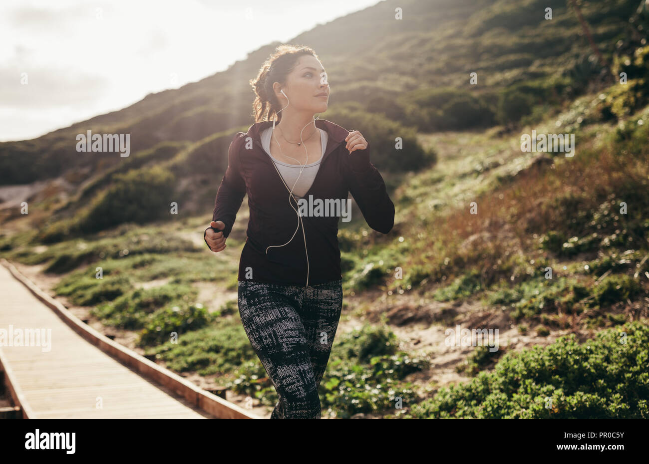 Femme en marche à l'extérieur et à la recherche à la vue. Les femmes faisant de l'exercice de jogging sur le chemin par la montagne. Banque D'Images