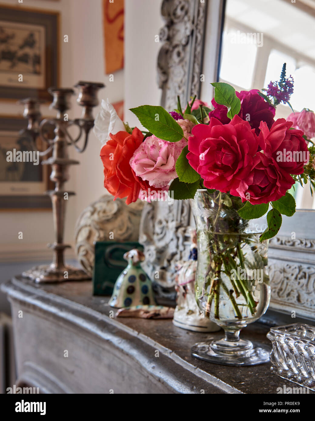 Les roses coupées en vase en verre sur la cheminée Banque D'Images