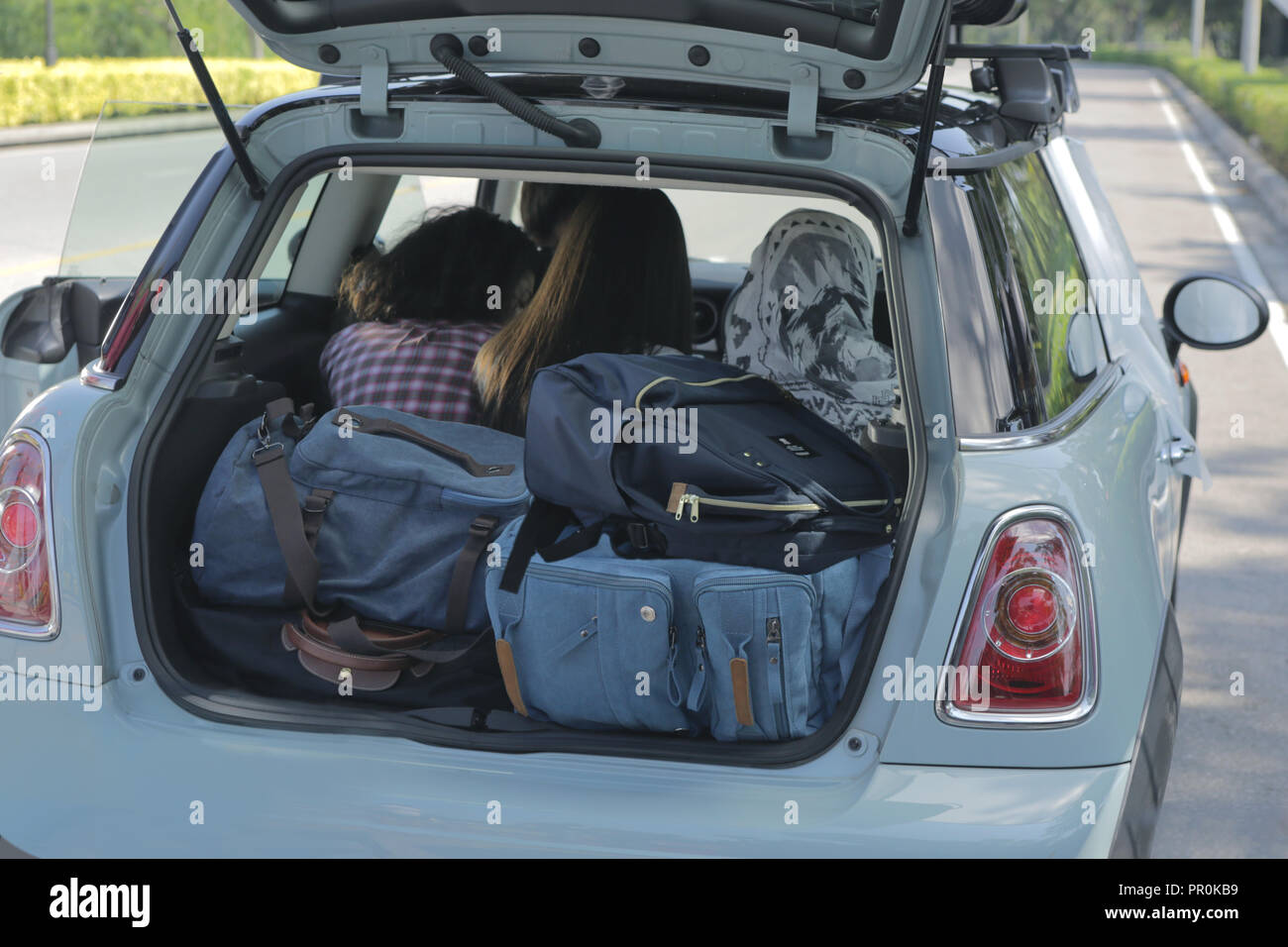 Les trois filles et les sacs à dos chargés dans le coffre de voiture prêt pour aller en voyage long week-end. Banque D'Images