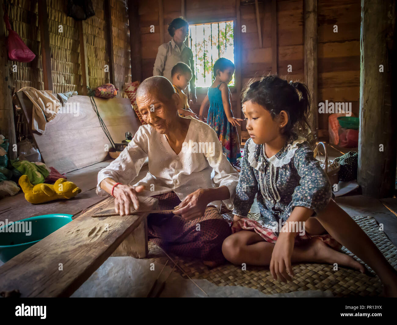 Vieille Femme faisant l'encens comme enfant regarde, village près de Siem Reap, Cambodge, Indochine, Asie du Sud-Est, l'Asie Banque D'Images