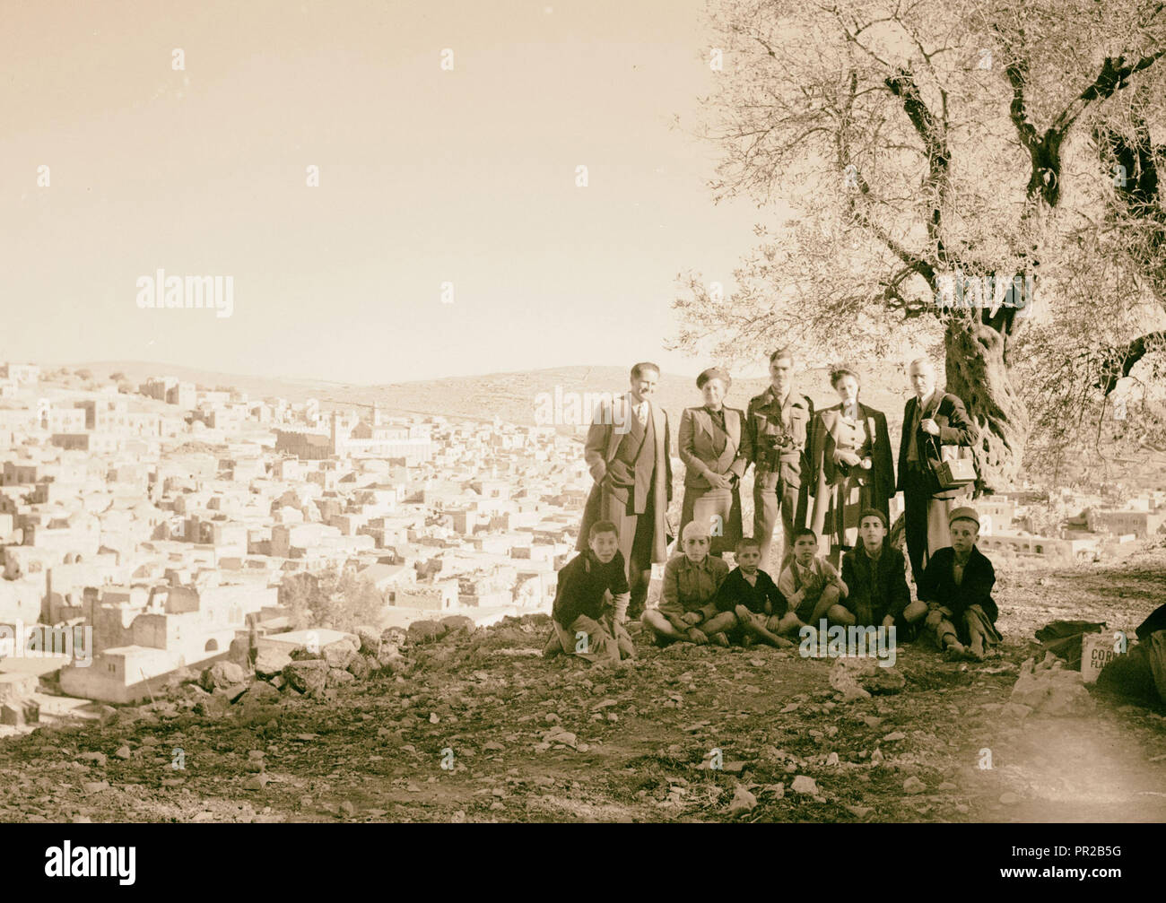 Eric Matson avec appareil photo (debout à droite) avec des adultes et d'enfants arabes, sur une colline donnant sur Hébron. 1935, en Cisjordanie Banque D'Images