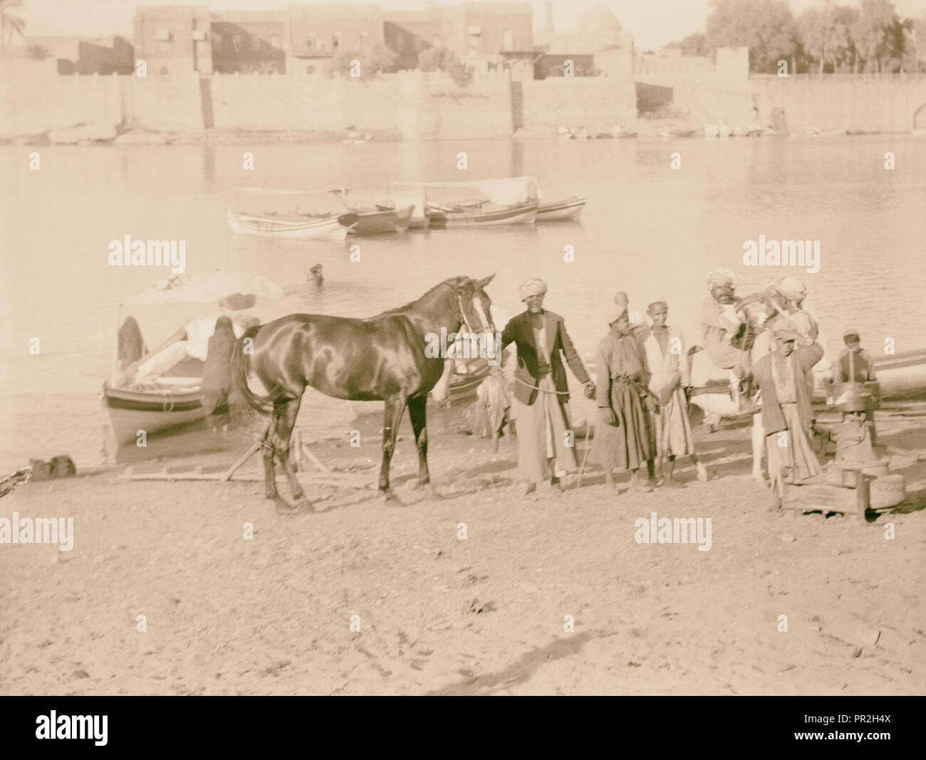 L'Iraq, les hommes & horse à côté, en face de ville fortifiée. 1932, l'Iraq Banque D'Images