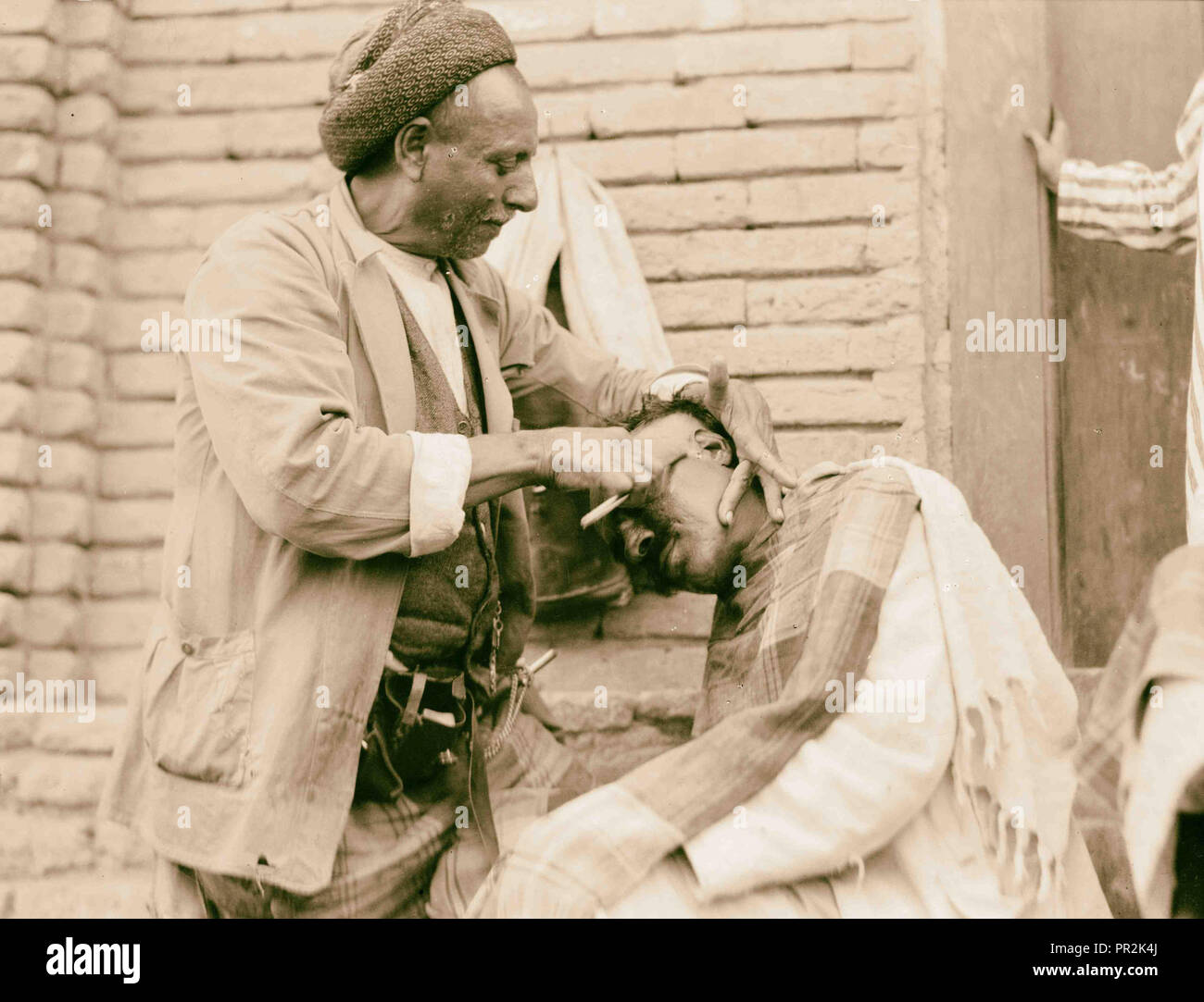 L'Iraq. (Mésopotamie). Bagdad. Vues, scènes de rue, et les types. Salon de coiffure de la rue au travail. 1932, l'Iraq, Bagdad Banque D'Images