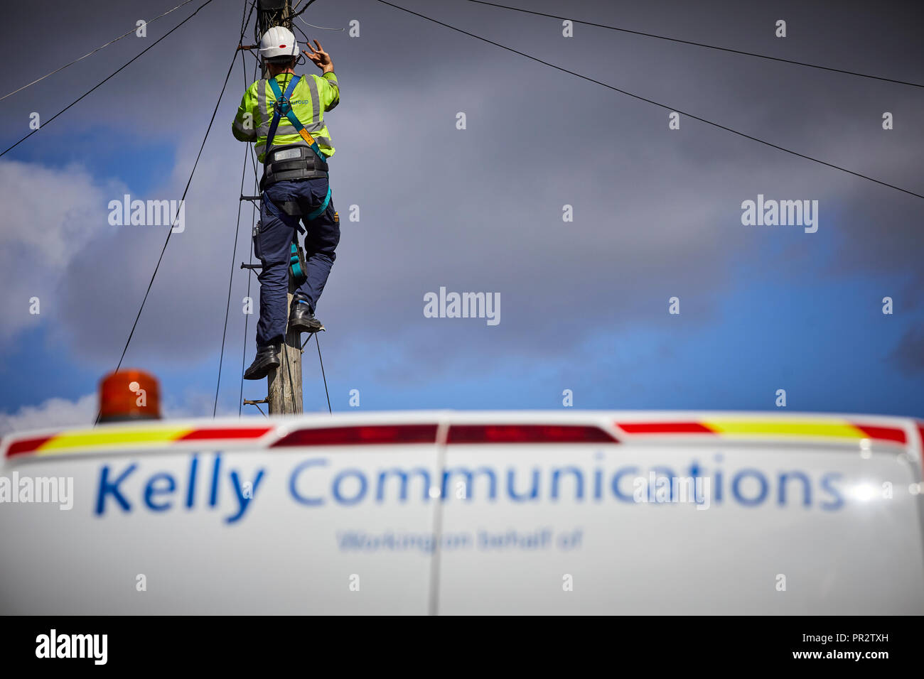 Telecome entrepreneurs Ingénieur de Kelly Communications escalade un poteau téléphonique pour fixer une ligne téléphonique sous-traitant travaillant pour BT Openreach en ma Banque D'Images