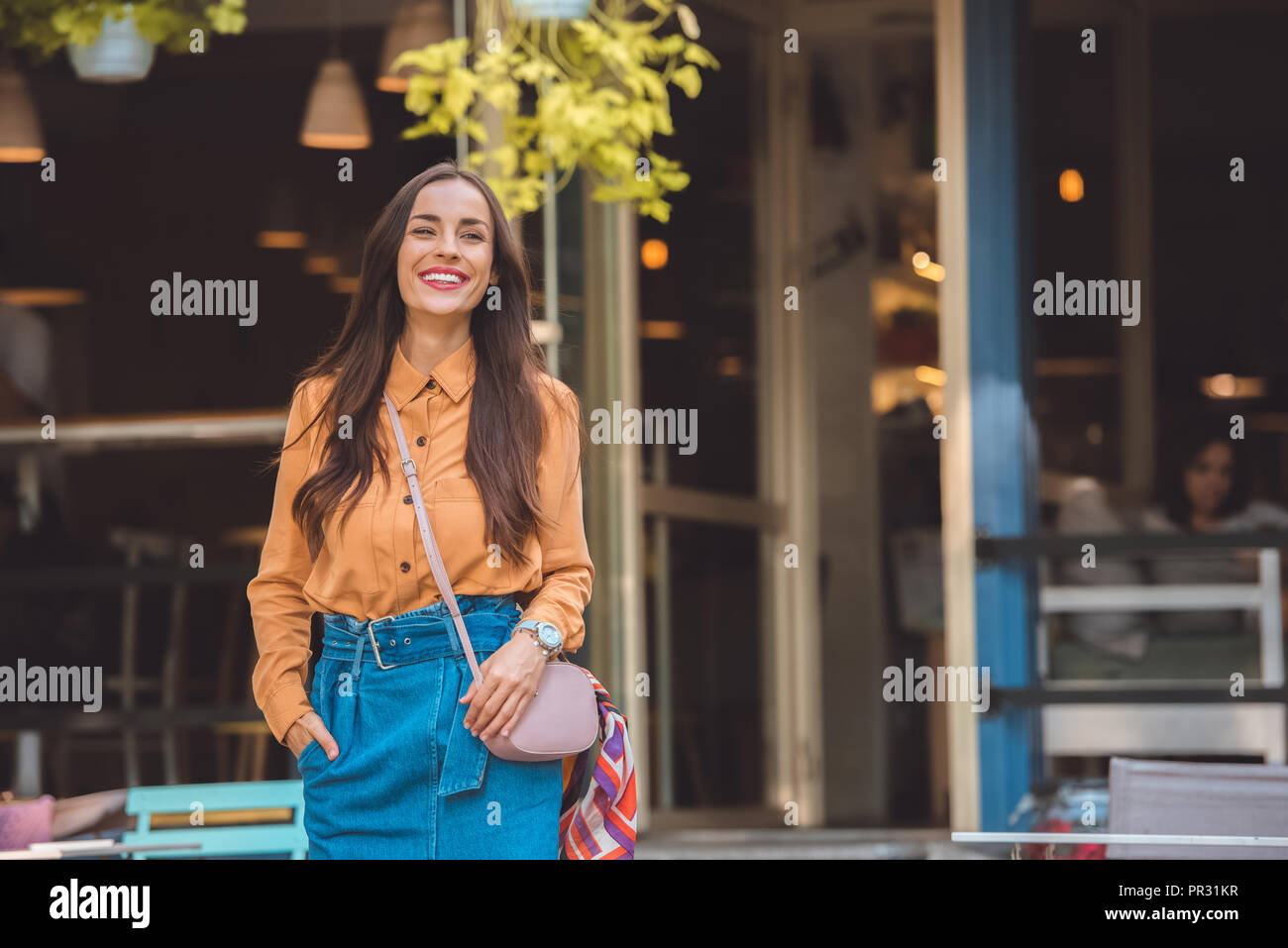 Smiling woman avec sac à main élégant à urban street Banque D'Images