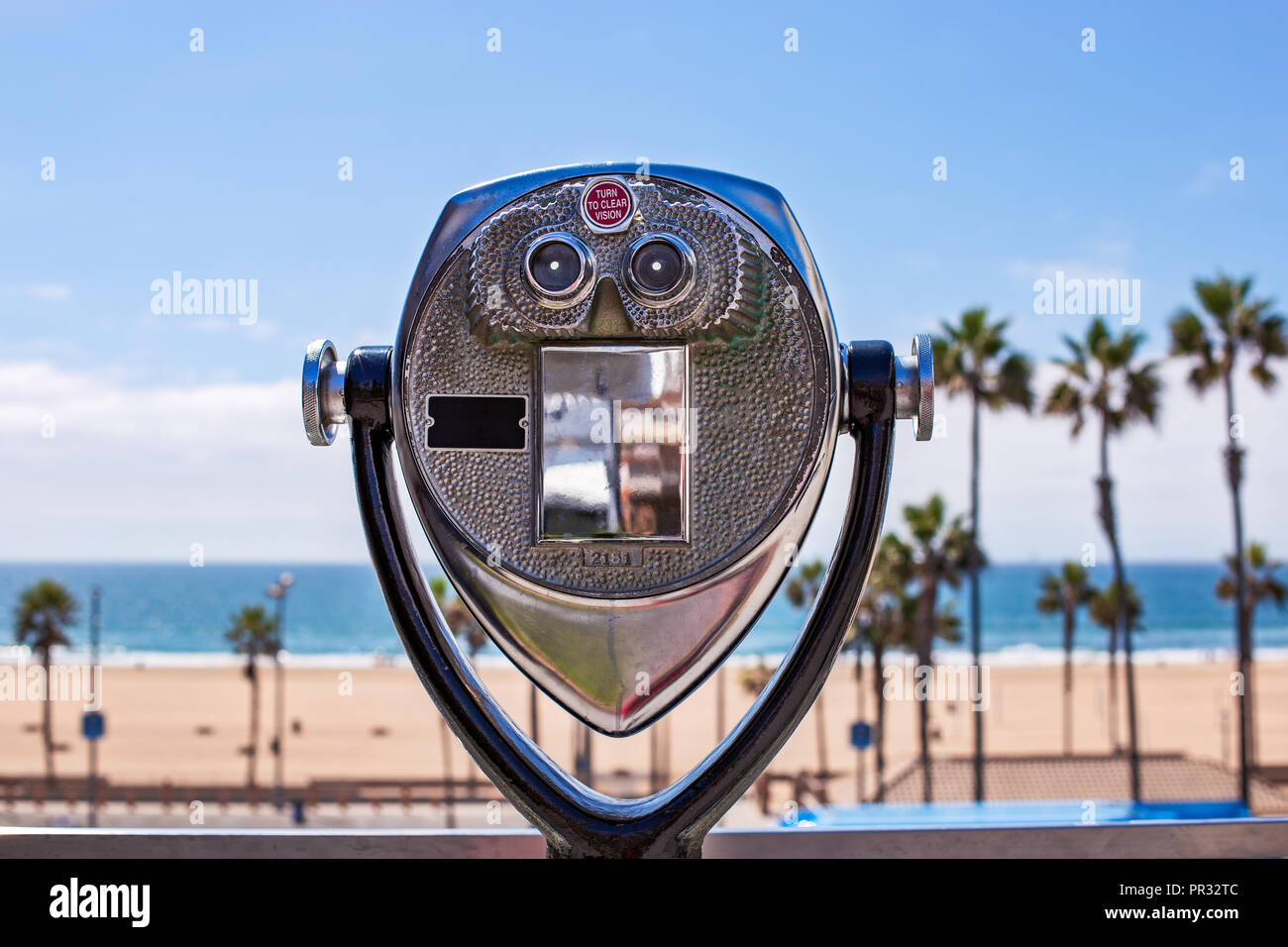 Jumelles à pièces qui donnent sur une scène de plage avec des palmiers, du sable et l'océan Pacifique à Huntington Beach, en Californie Banque D'Images