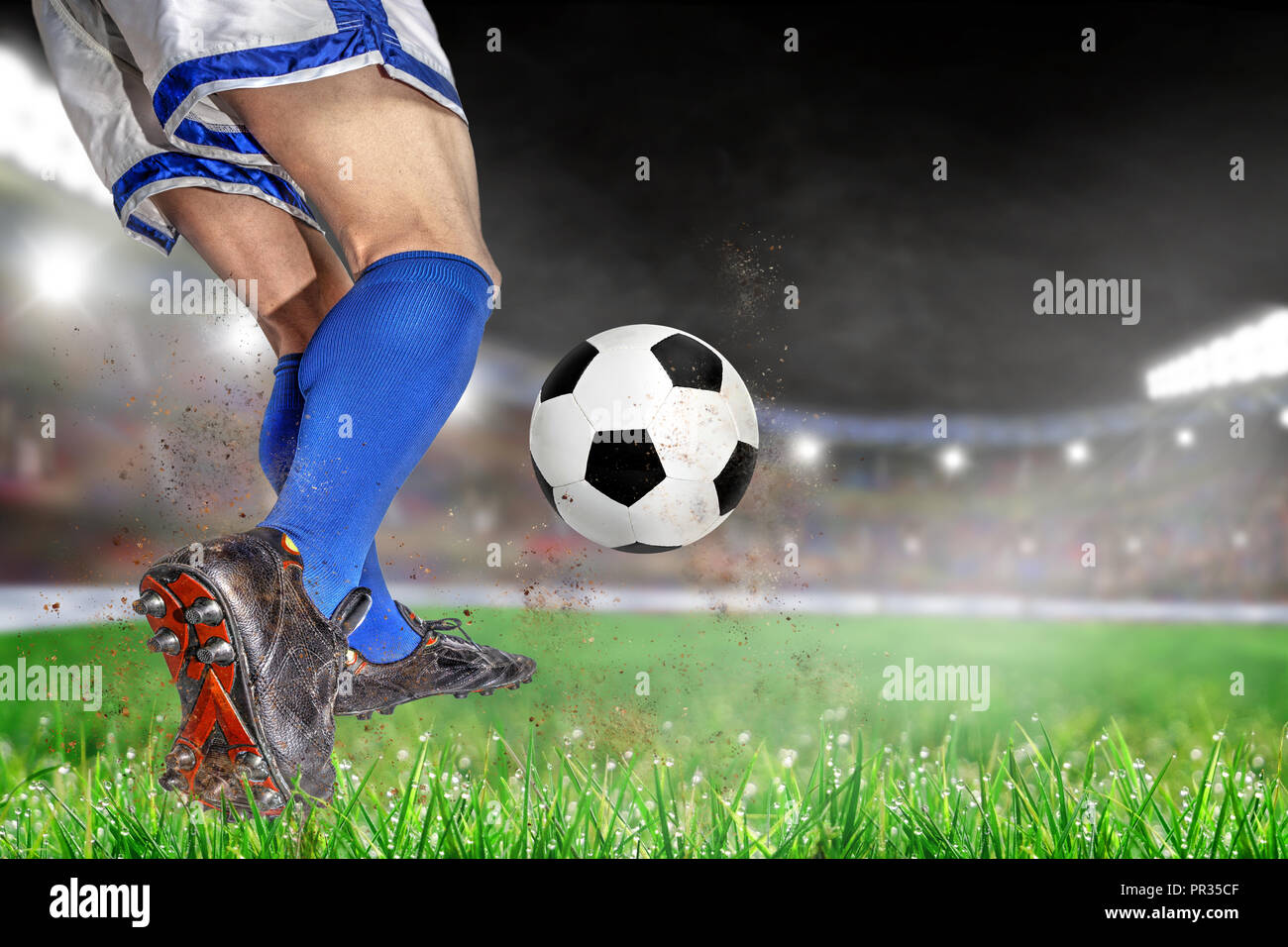 Joueur de football en action avec le football en pleine lumière stade en plein air. L'accent sur le premier plan et ballon de soccer avec une faible profondeur de champ sur un arrière-plan Banque D'Images