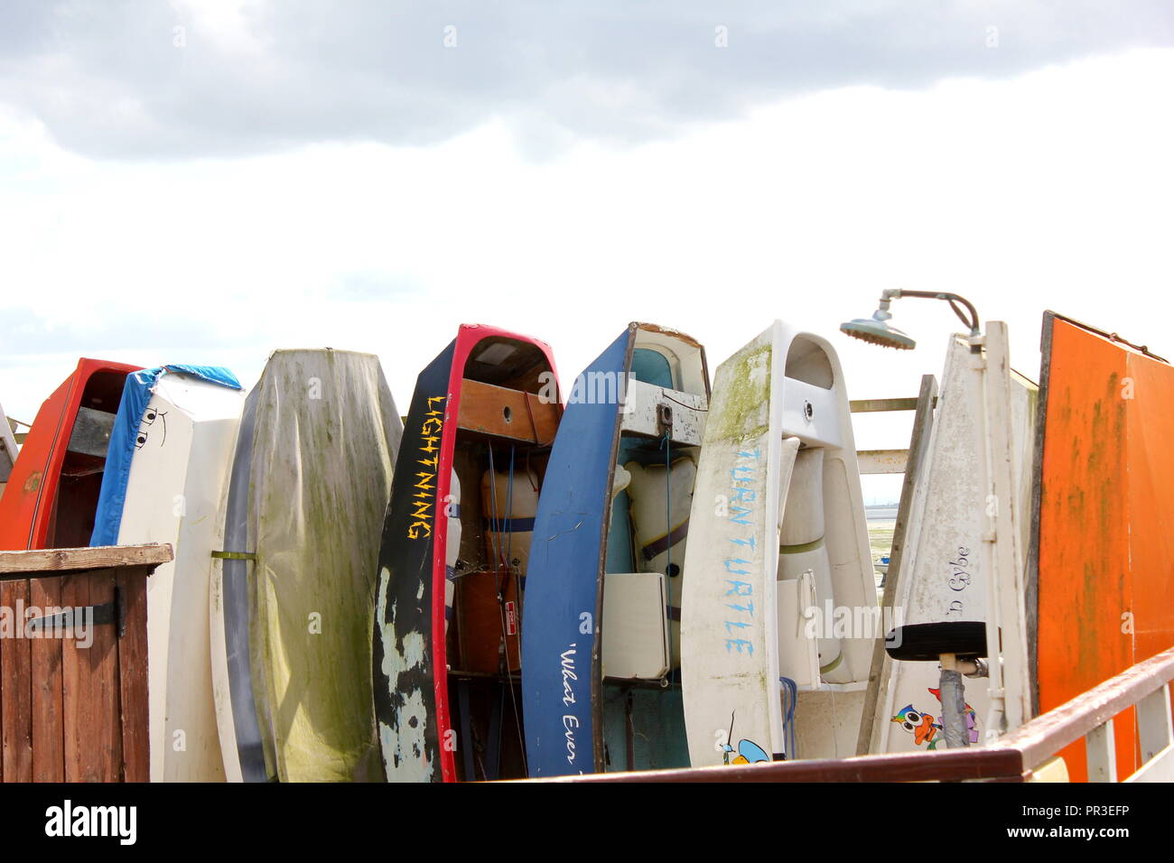 Dingy,s en différentes couleurs empilés verticalement sur une ligne Leigh on Sea, Essex Banque D'Images