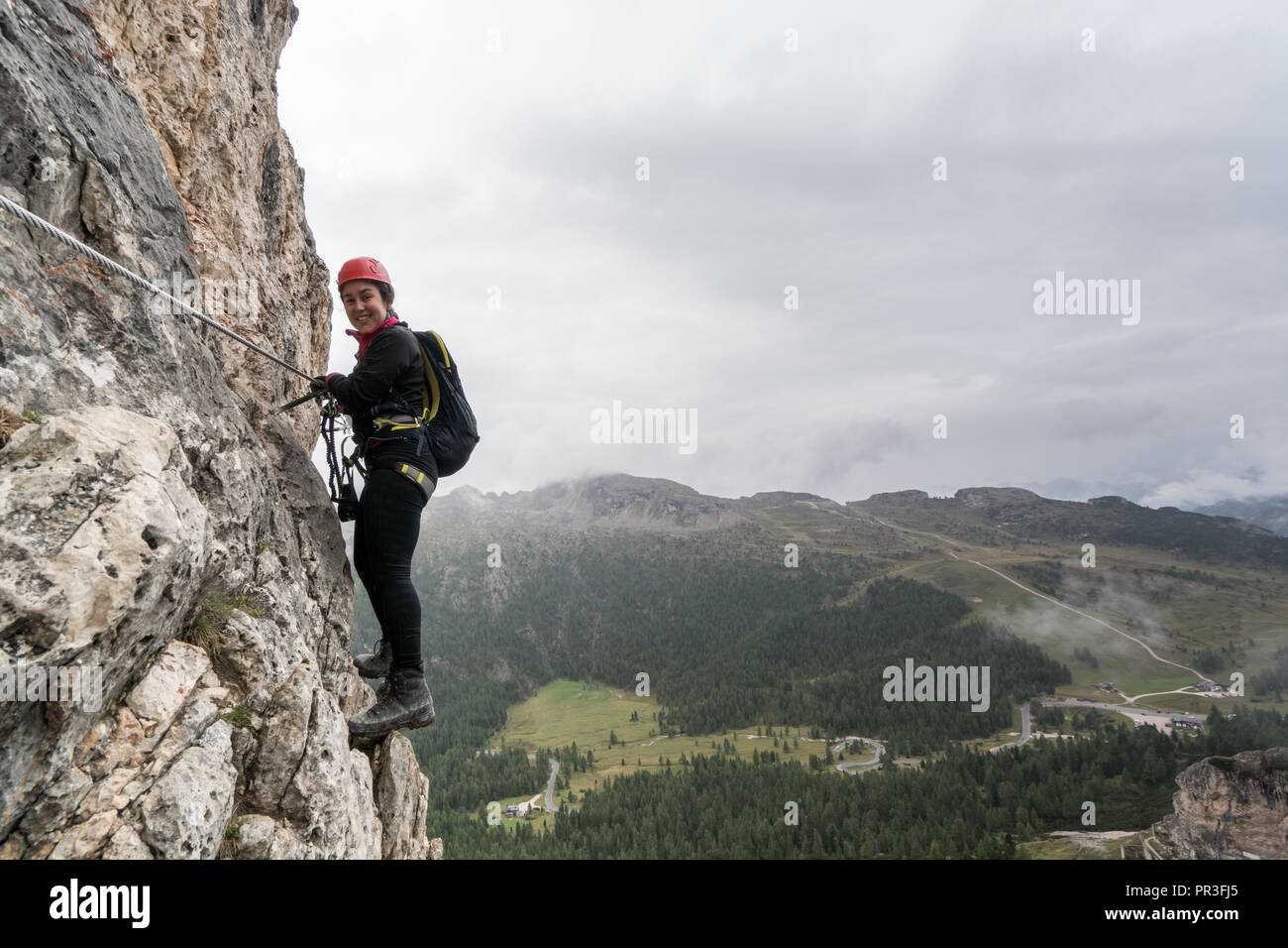 Les jeunes femmes attrayantes d'alpiniste sur une pente raide et exposé Via Ferrata en Alta Badia dans le Tyrol du Sud dans les Dolomites italiennes Banque D'Images