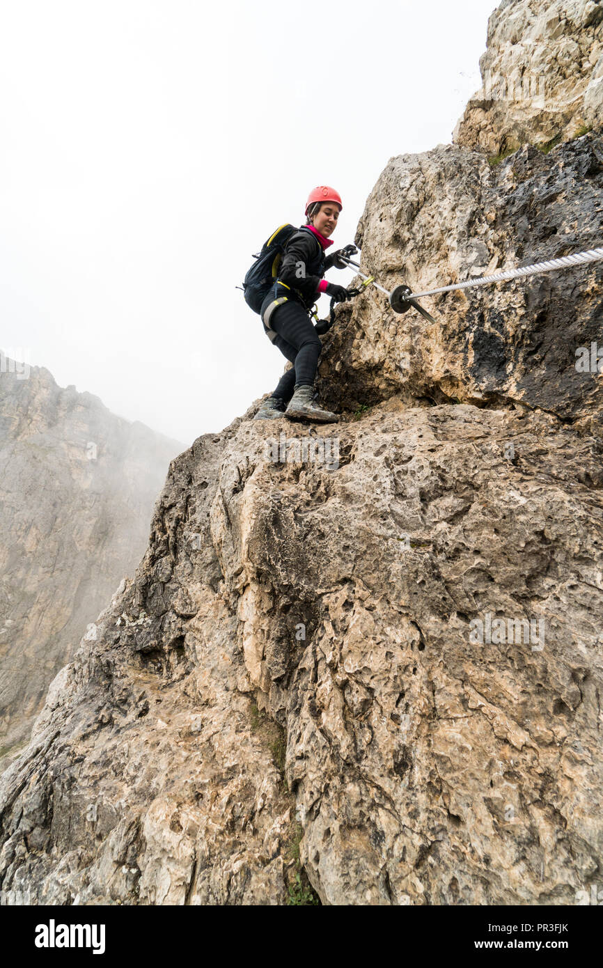 Les jeunes femmes attrayantes d'alpiniste sur une pente raide et exposé Via Ferrata en Alta Badia dans le Tyrol du Sud dans les Dolomites italiennes Banque D'Images