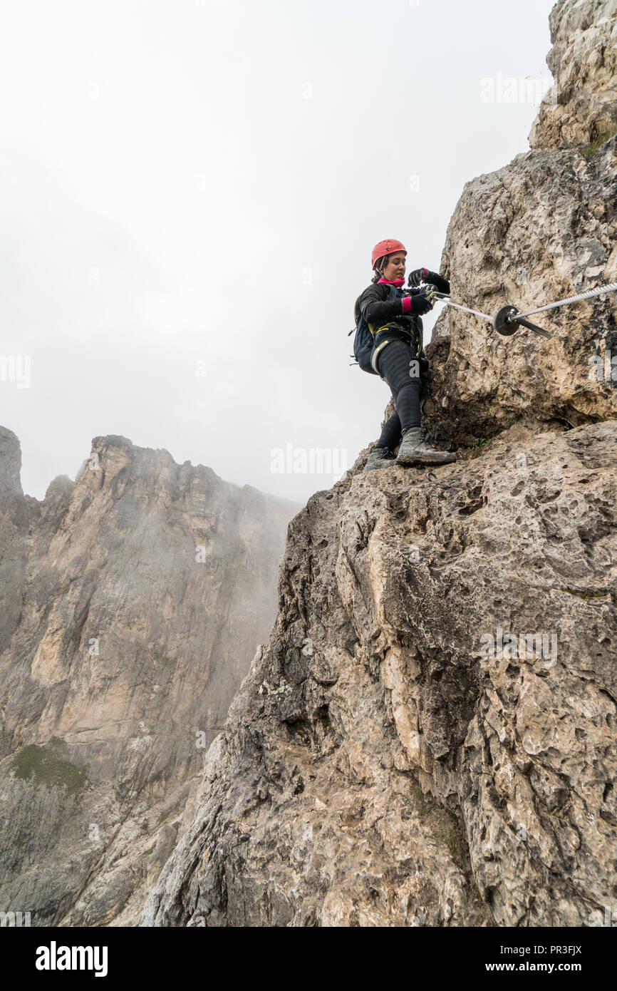 Les jeunes femmes attrayantes d'alpiniste sur une pente raide et exposé Via Ferrata en Alta Badia dans le Tyrol du Sud dans les Dolomites italiennes Banque D'Images