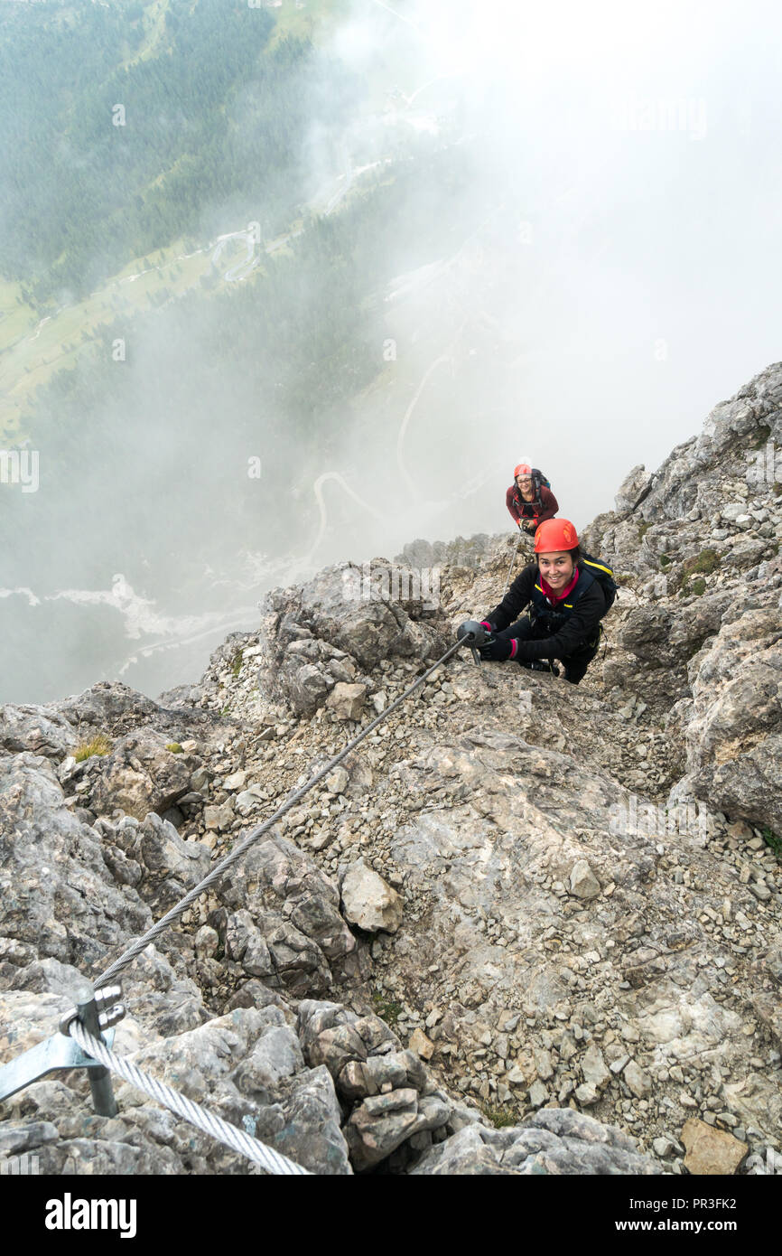Deux jeunes femmes attrayantes d'alpinistes sur une pente raide et exposé Via Ferrata en Alta Badia dans le Tyrol du Sud dans les Dolomites italiennes Banque D'Images