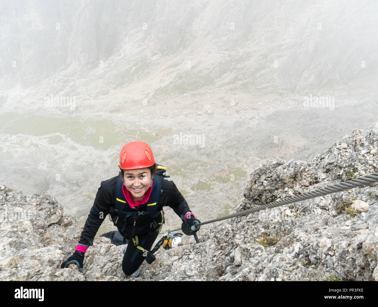 Les jeunes femmes attrayantes d'alpiniste sur une pente raide et exposé Via Ferrata en Alta Badia dans le Tyrol du Sud dans les Dolomites italiennes Banque D'Images