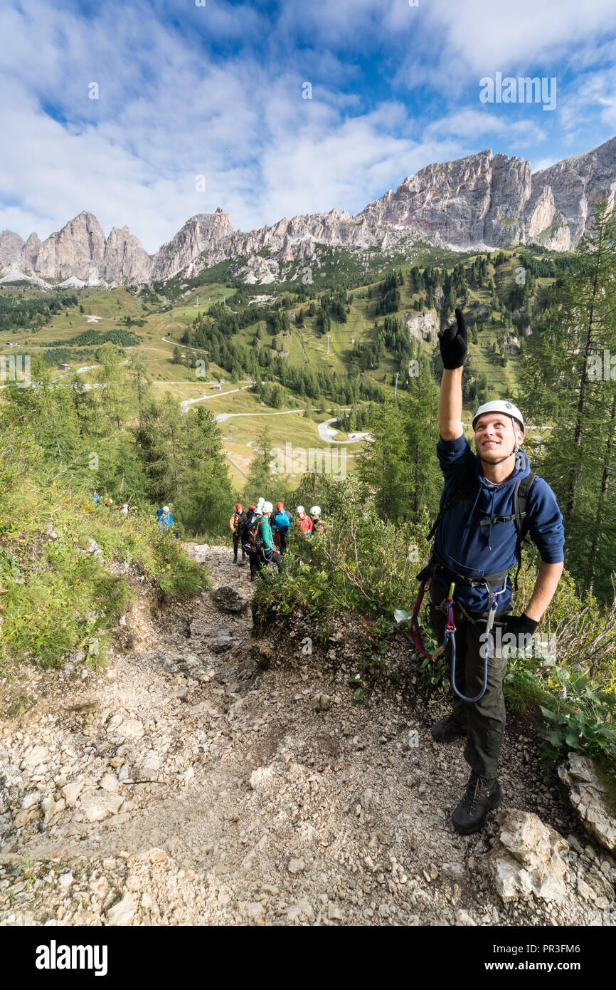 Young male climber situés jusqu'à une via ferrata dans les Dolomites et beaucoup de gens debout derrière lui Banque D'Images