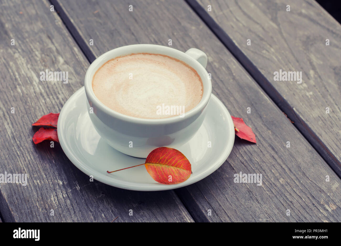 Tasse à café sur un fond de bois. La nature morte de latte avec les feuilles d'automne. Banque D'Images