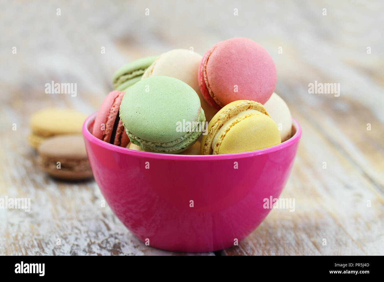 Macarons croquants colorés en rose bowl sur la surface en bois rustique avec copie espace Banque D'Images