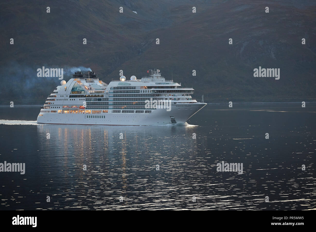 Le navire de croisière Seabourn, Ovation, voiles à travers le Lauksundet, près de Skjervøy, au nord de l'Arctique norvégien cercle au coucher du soleil. Banque D'Images