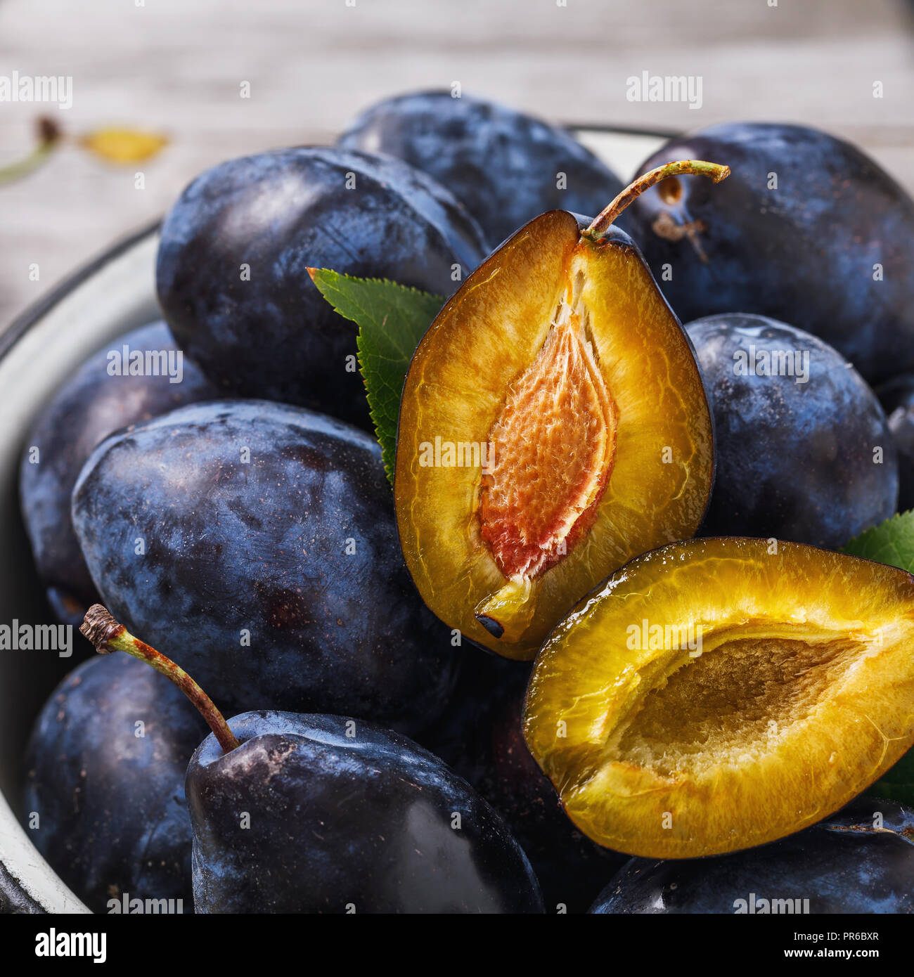 Plaque pleine de fruits pruneaux mûrs sur table en bois close-up Banque D'Images