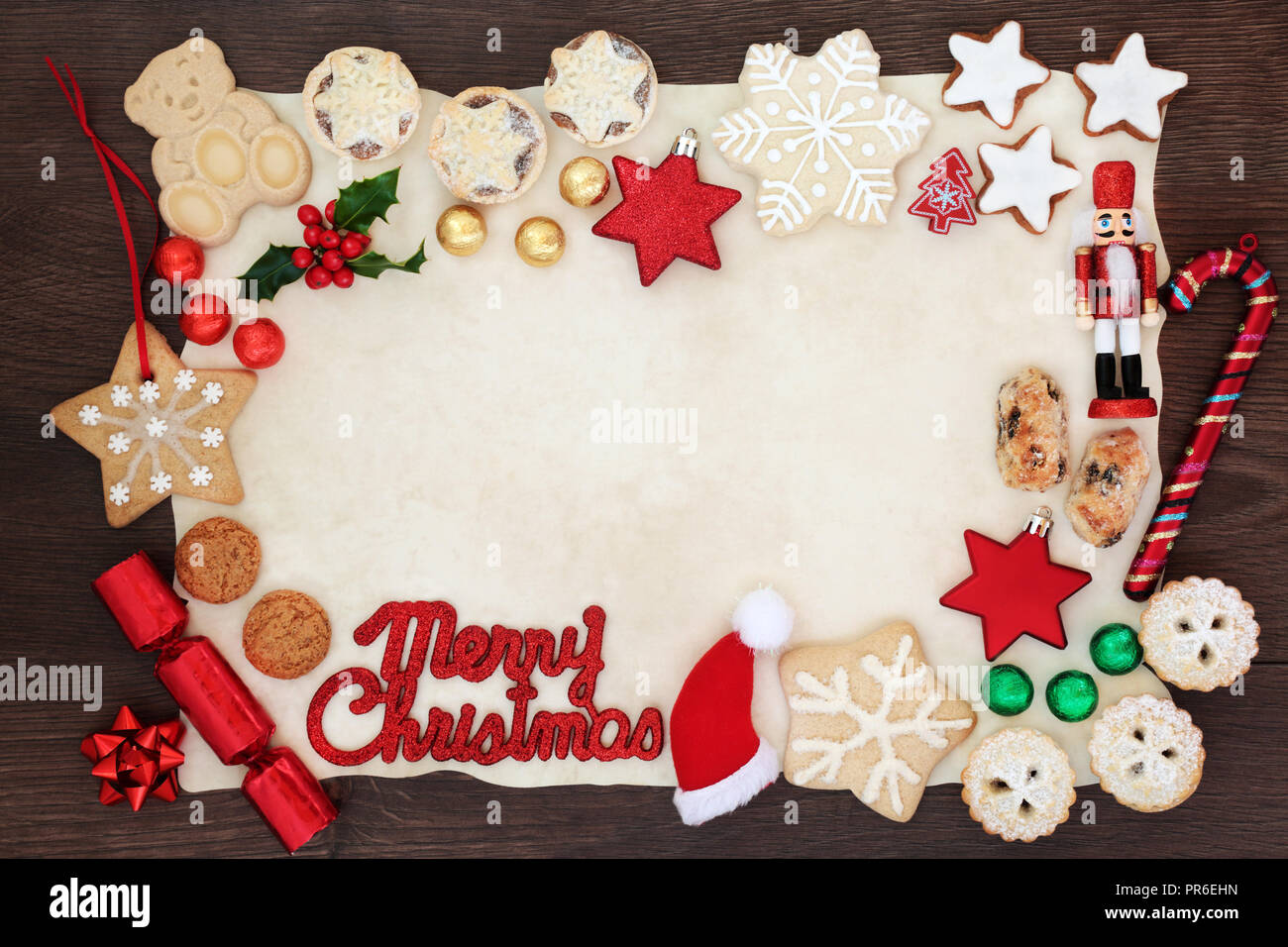 Joyeux Noël arrière-plan frontière avec l'inscription, des décorations de l'arbre, des biscuits, des gâteaux, de la flore et d'hiver en aluminium sur le papier sulfurisé sur bois rustique Banque D'Images