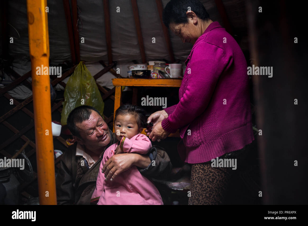 Les grands-parents vu holding et prendre soin de leur petite fille durant un matin tôt à l'intérieur de leur maison, près de la ville de Uyanga dans la province, le sud de la Mongolie Övörkhangai. Banque D'Images