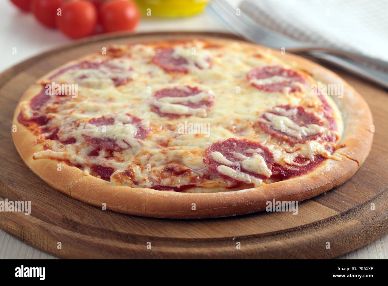 Pizza au salami et fromage sur une planche en bois Banque D'Images