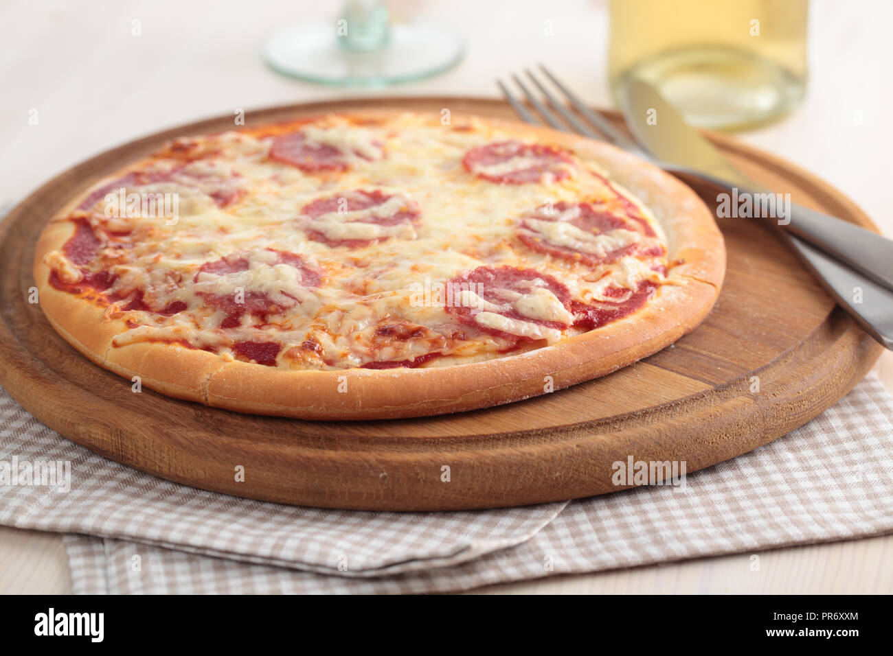 Pizza au salami et fromage sur une planche en bois Banque D'Images