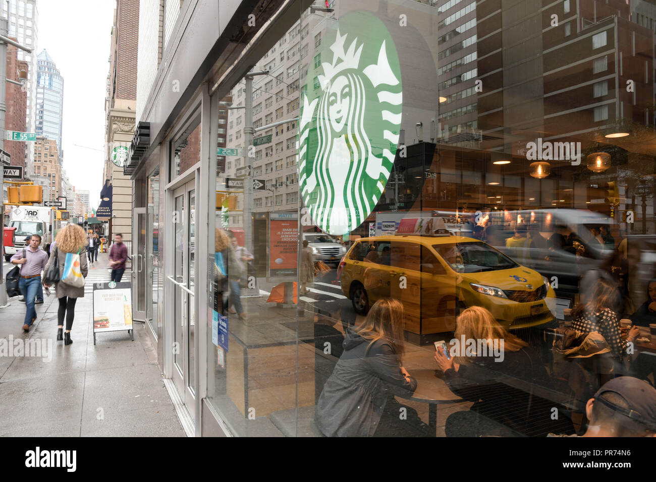 Les clients de remplir un Starbucks sur la Cinquième Avenue à New York City sur un ciel nuageux matin de septembre. Banque D'Images