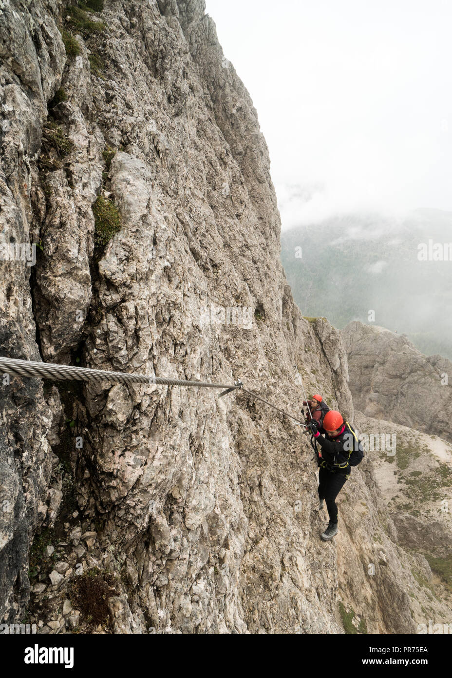 Deux jeunes femmes attrayantes d'alpinistes sur une pente raide et exposé Via Ferrata en Alta Badia dans le Tyrol du Sud dans les Dolomites italiennes Banque D'Images