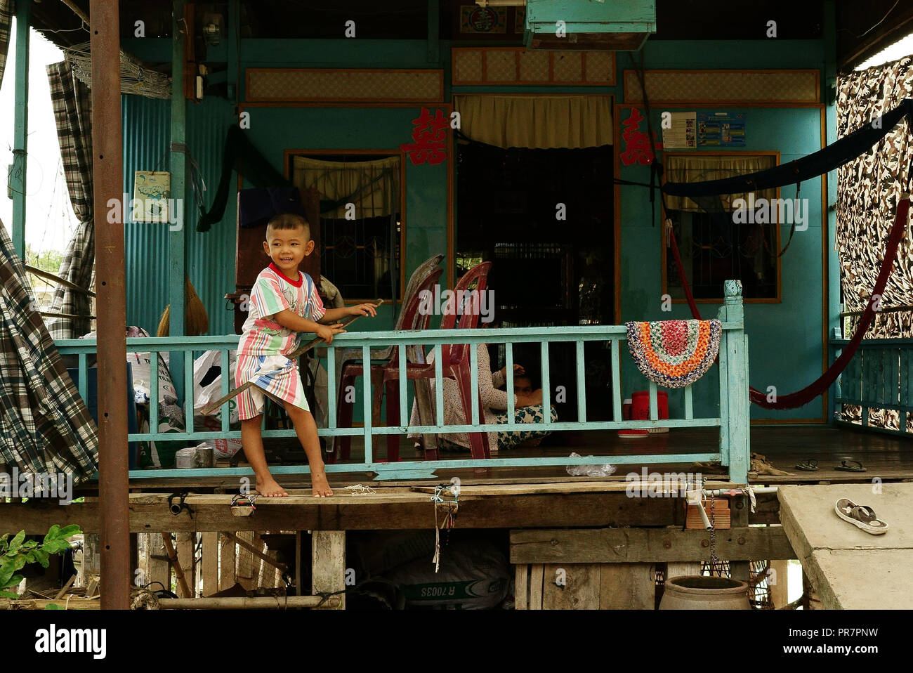 Kid en face de sa maison sur pilotis, le long de la rivière Hau, Chau Doc, Delta du Mékong, au Vietnam, à la frontière cambodgienne. Banque D'Images