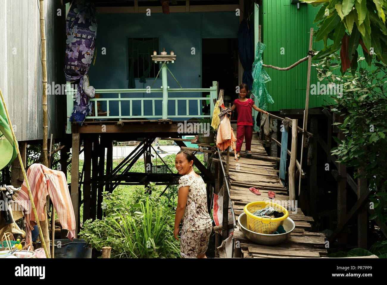 Femme et sa fille devant leur maison sur pilotis, le long de la rivière Hau, Chau Doc, Delta du Mékong, au Vietnam, à la frontière cambodgienne. Banque D'Images