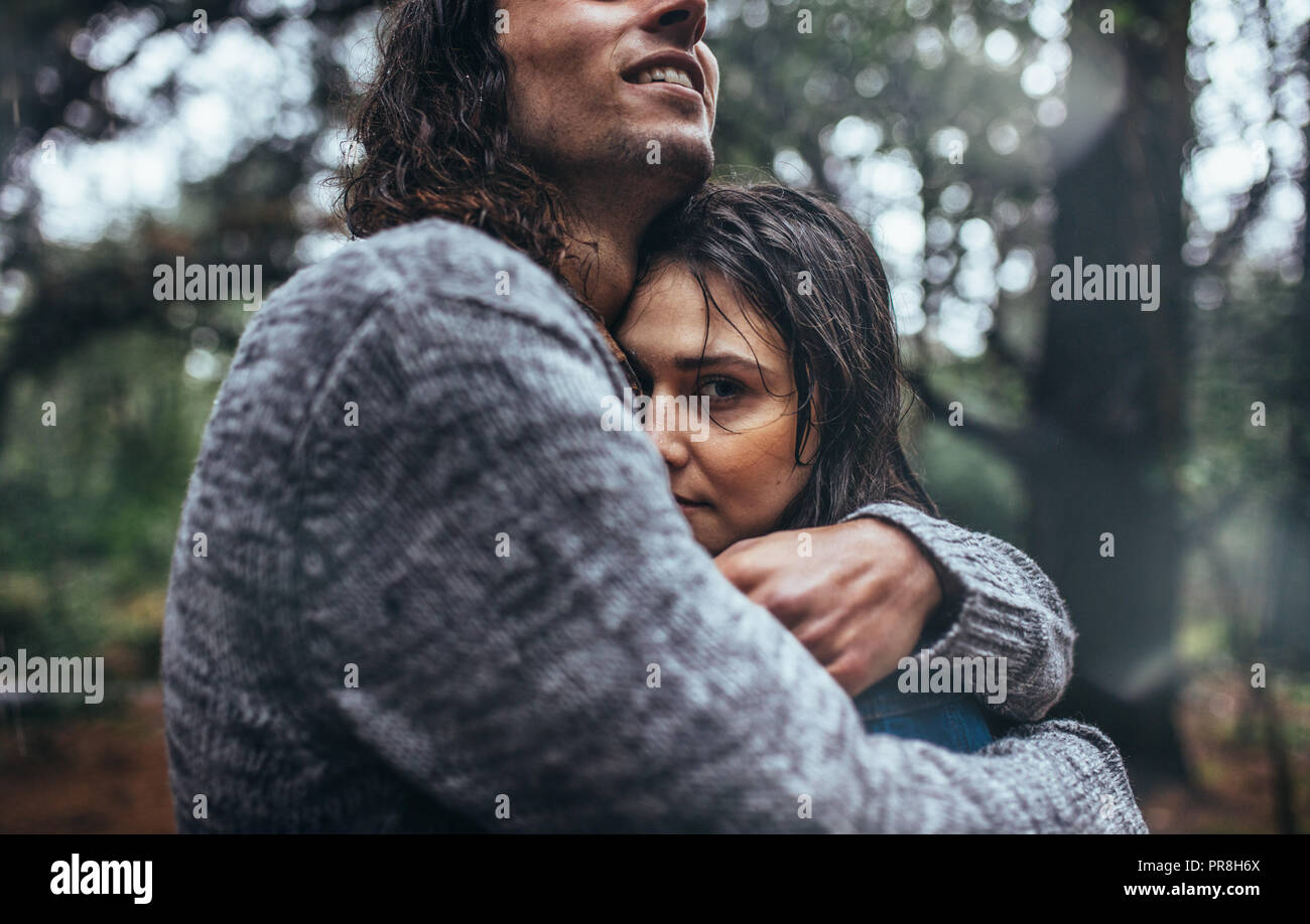 Femme humide dans les bras de son petit ami dans la forêt. Couple romantique en forêt dans la pluie. Banque D'Images