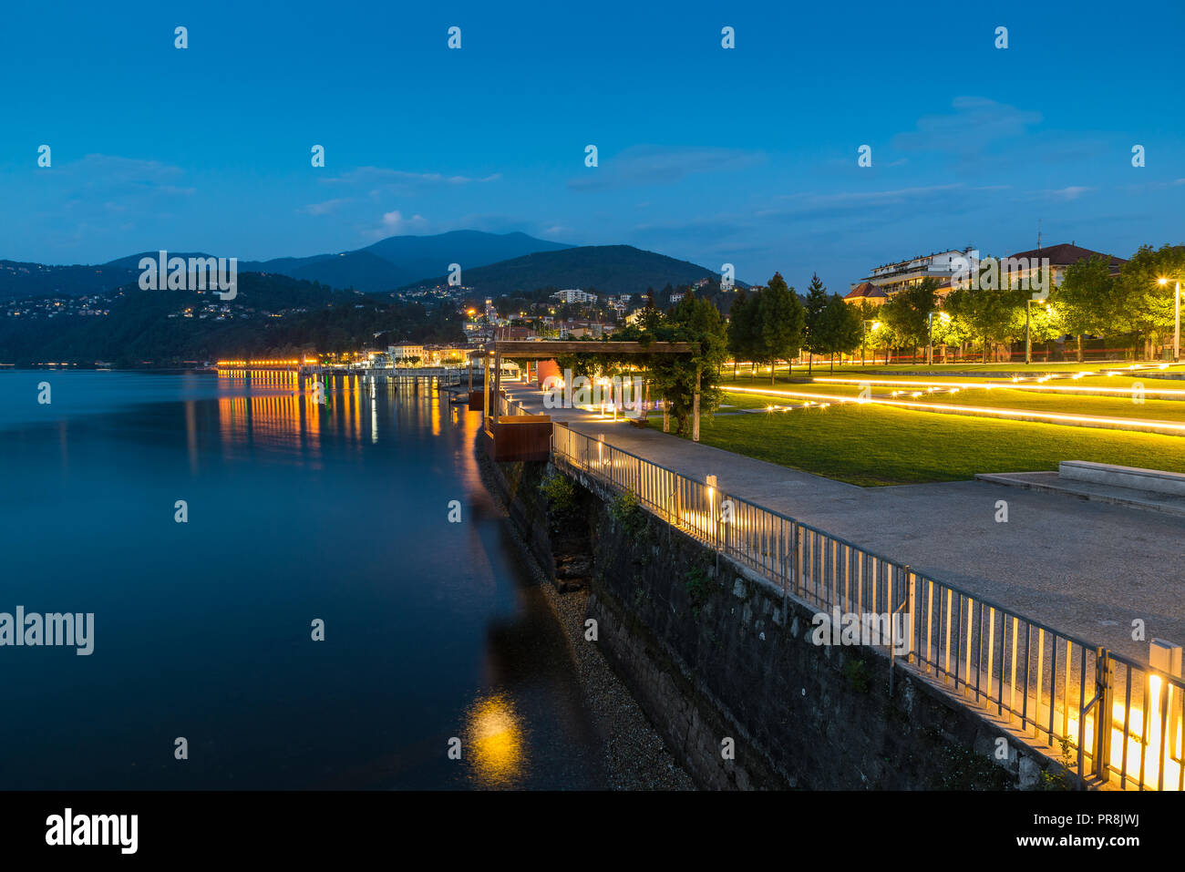 Promenade au bord du lac au crépuscule. Le Lac Majeur et ville touristique de Luino avec sa belle lakefront allumé sur un beau soir d'été Banque D'Images