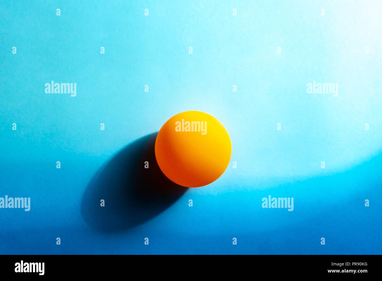Coucher du soleil par la mer minimaliste abstrait. Balle de ping-pong sur fond bleu du papier. Banque D'Images