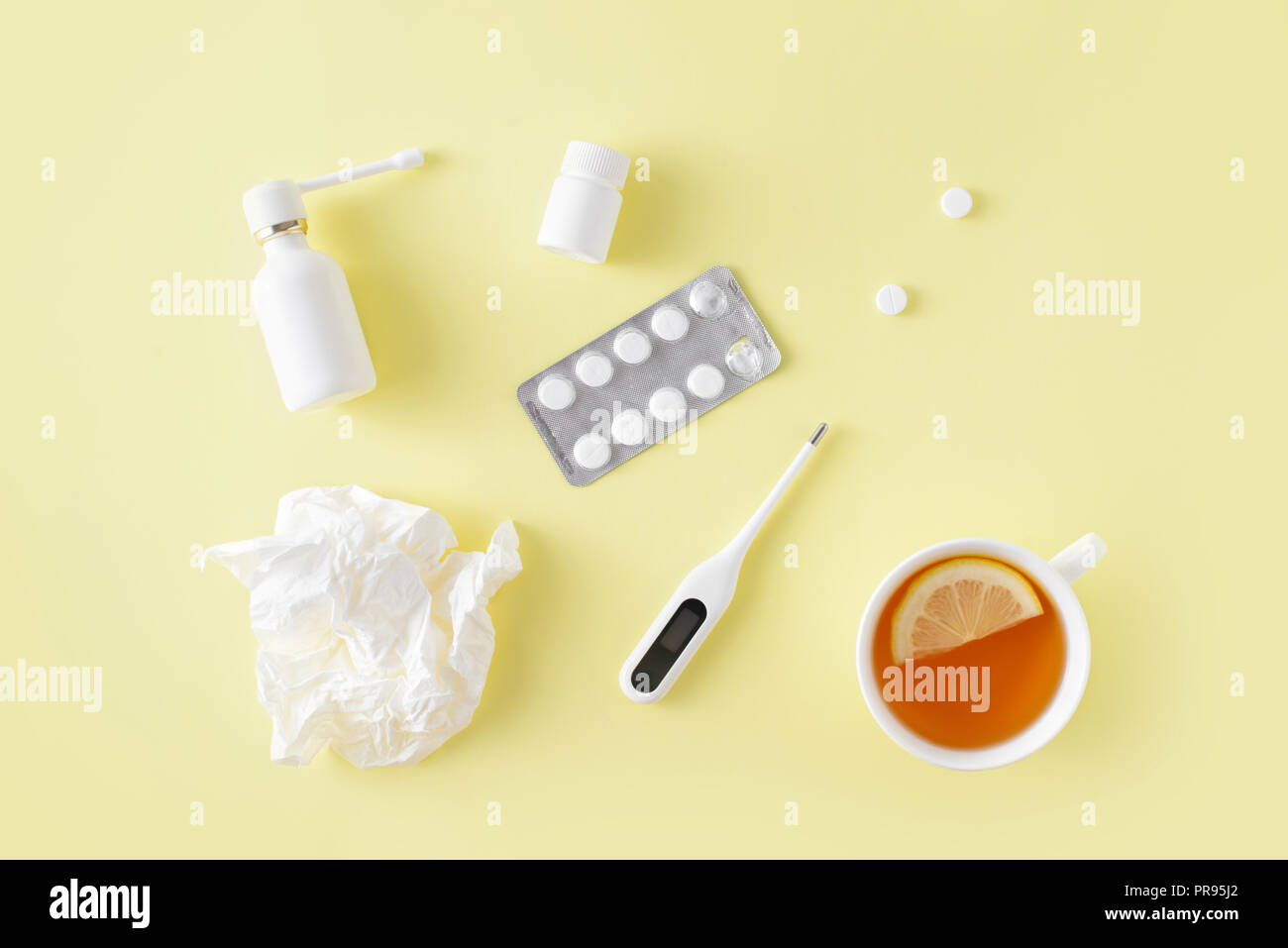 Le traitement du rhume et de la grippe. Comprimés, spray gorge, thermomètre, tasse de thé au citron simple sur fond jaune. La thérapie de soins de santé. Télévision lay, top vi Banque D'Images
