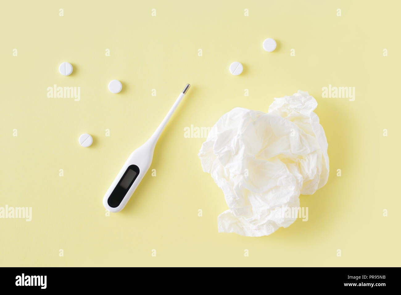 Pilules, serviettes pour le nez, un thermomètre sur fond jaune. Le traitement du rhume et de la grippe. Mise à plat, vue du dessus. Banque D'Images