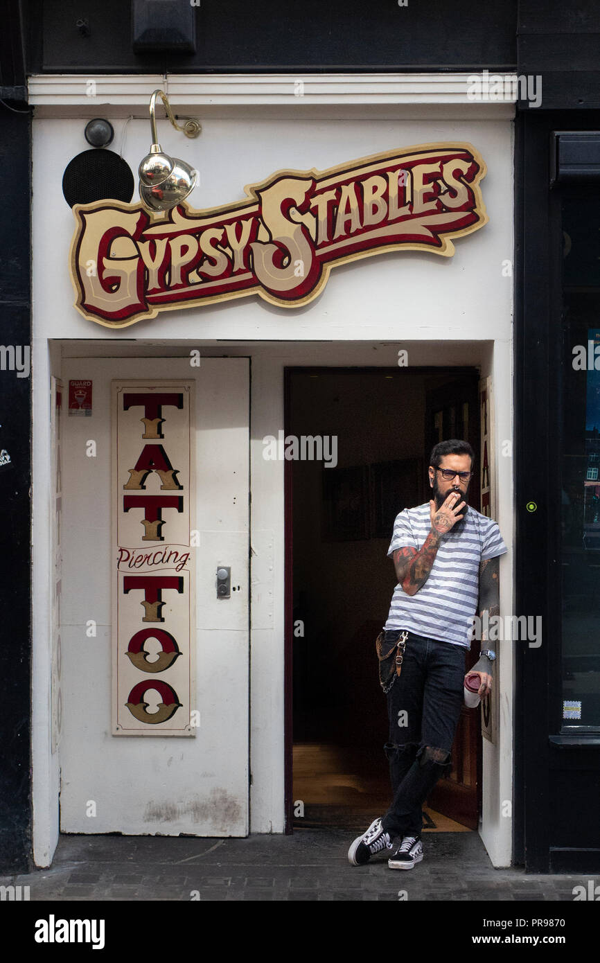 Un tatoueur très cool a une pause à l'extérieur de son studio de tatouage, Gypsy stables à Soho Banque D'Images