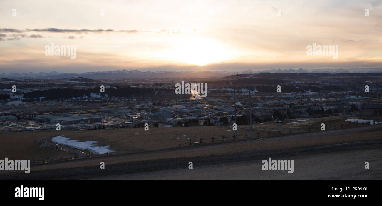 Donnant sur la ville de Cochrane, dans un coucher de soleil d'hiver avec les usines de la vapeur contre les Rocheuses. Banque D'Images