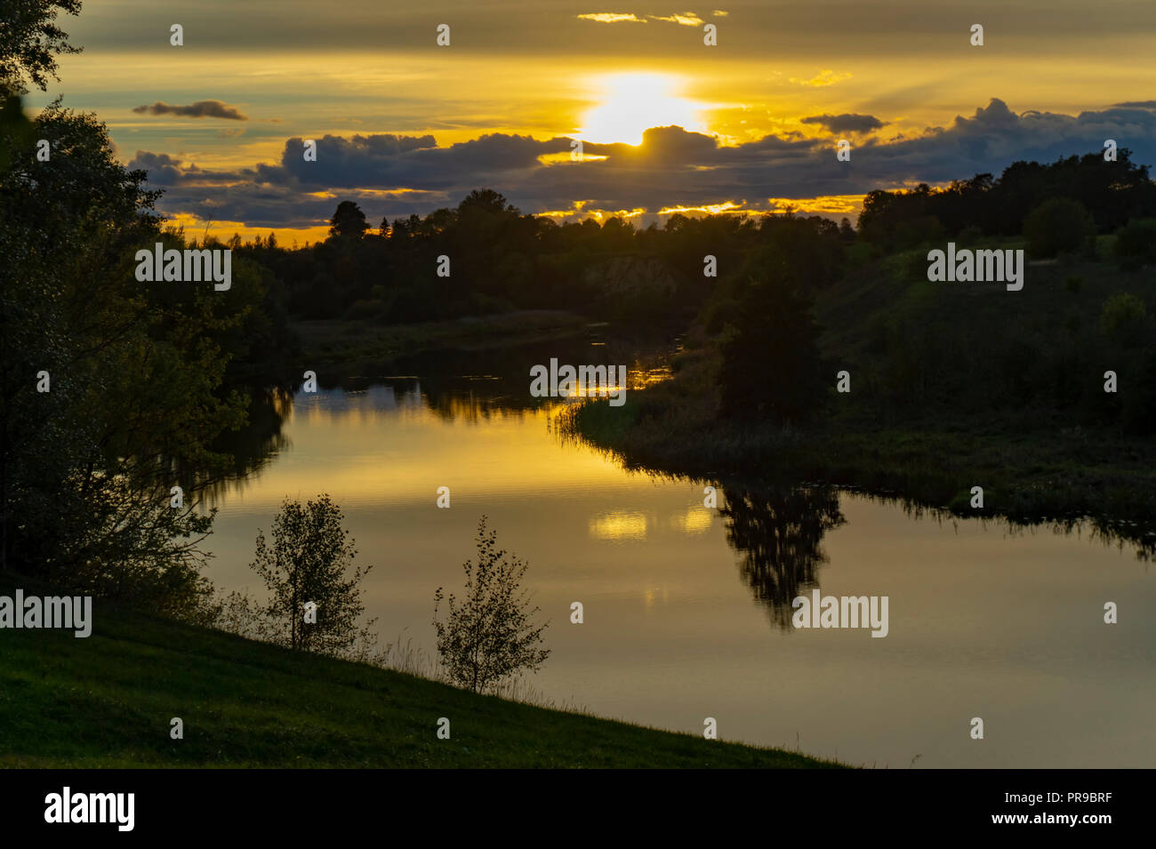 Couleurs de ciel coucher de soleil arbres et nuages reflétée dans rivière calme surface de l'eau Banque D'Images